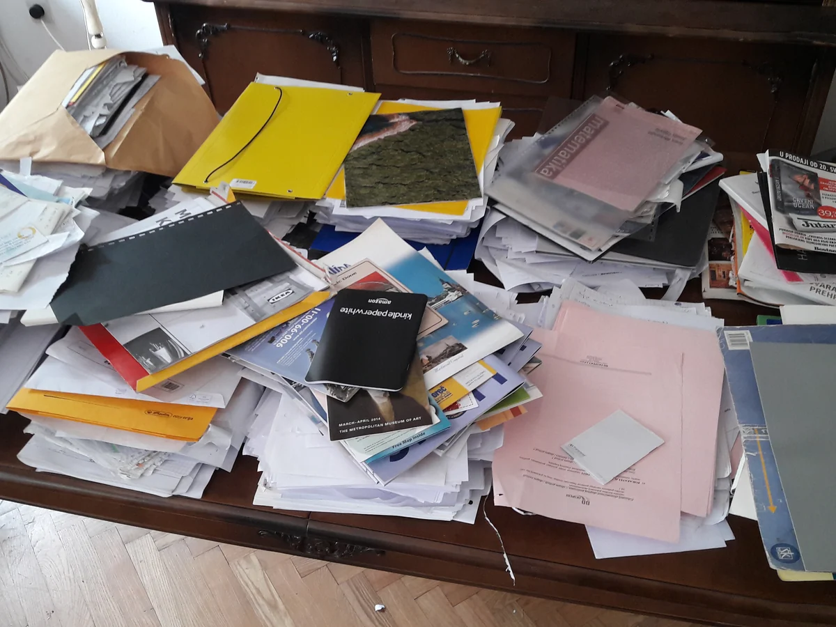 A table buried under piles of paper, folders and bills before the paperwork was sorted