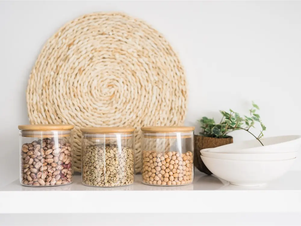 Glass jars of beans, lentils and chickpeas on a white shelf — zero waste without packaging