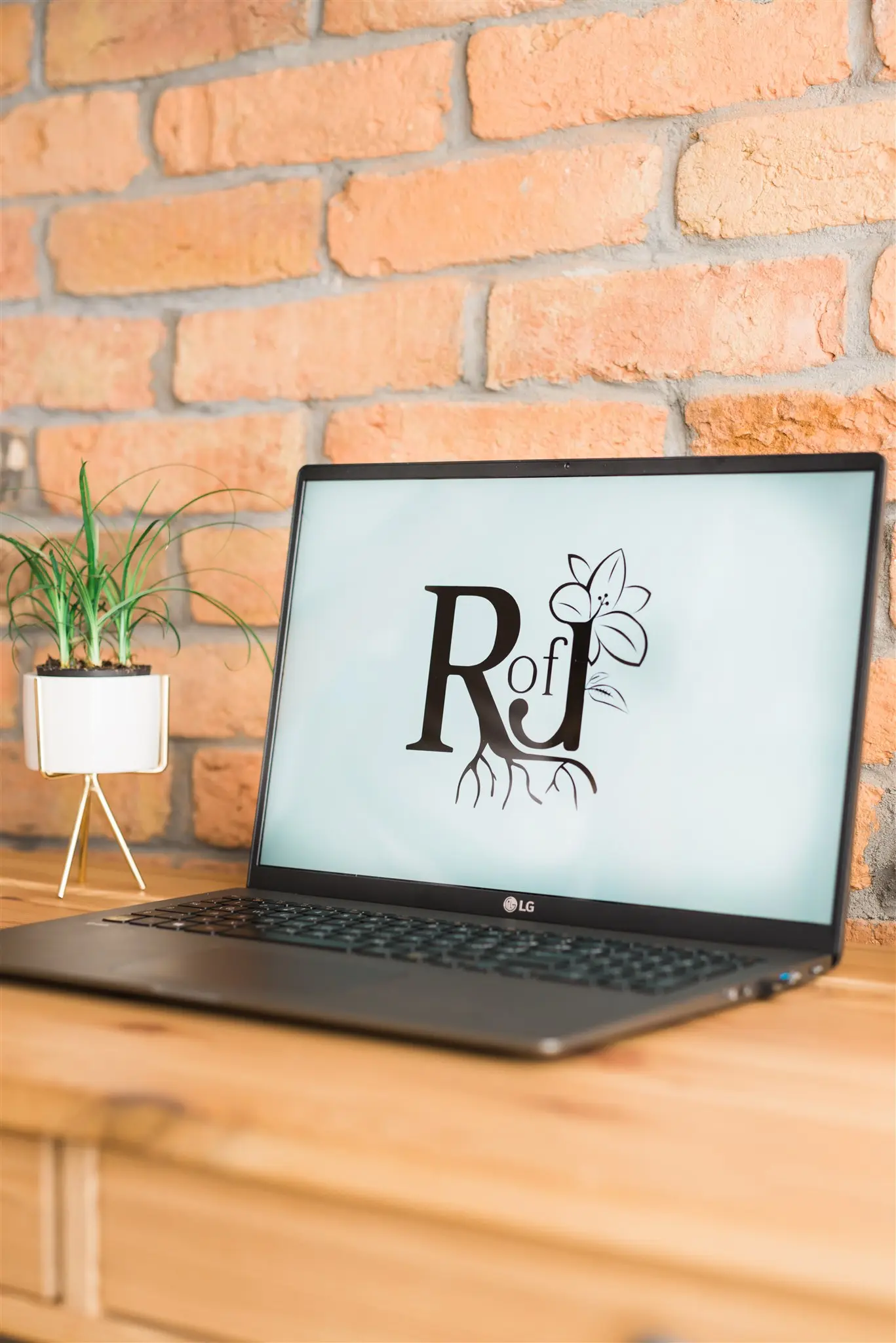 Laptop on a wooden desk showing the Root of Joy logo — building simple digital systems in Zagreb