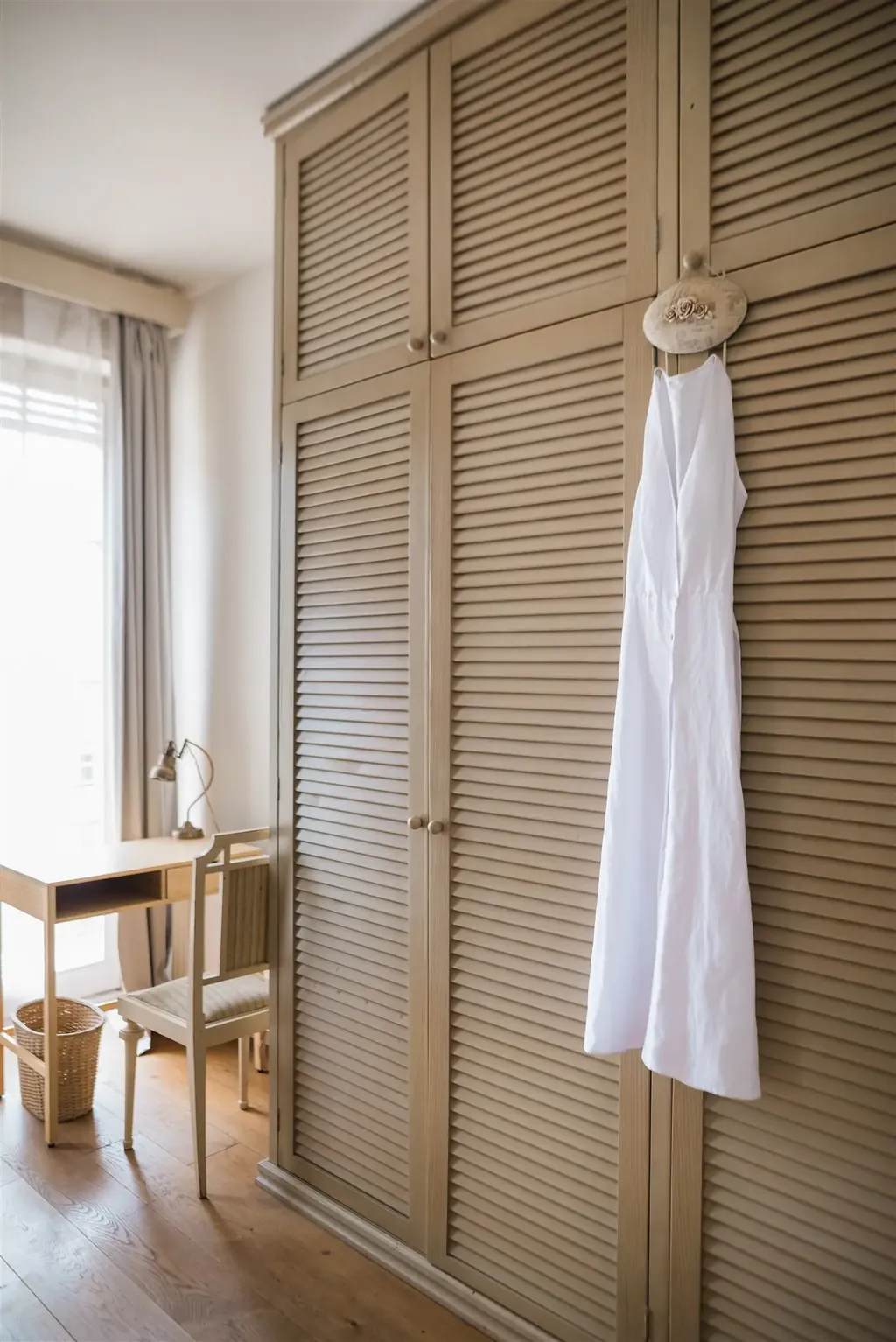 A white dress hanging on a louvred wardrobe door — the foundations of the KonMari® method, workshop in Zagreb