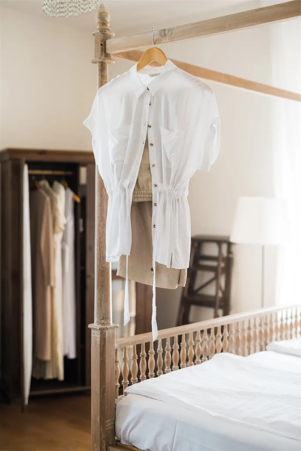 A white blouse on a hanger in front of an open wardrobe — the clothing workshop through the KonMari® method
