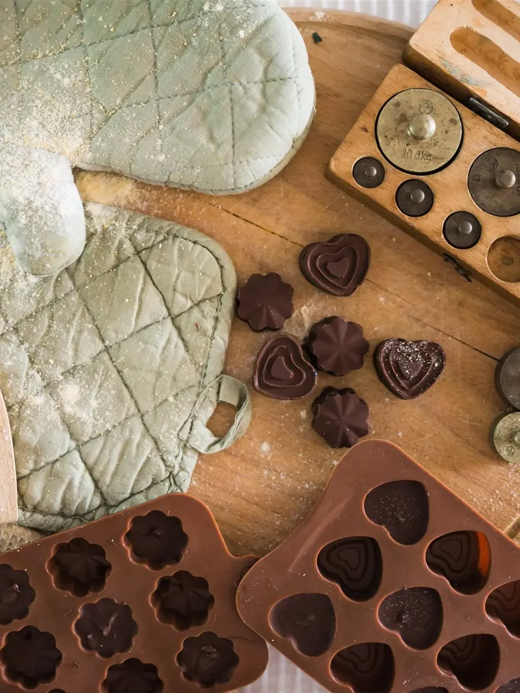 Oven mitts, chocolate pralines and brass weights on a wooden board — the kitchen workshop through the KonMari® method