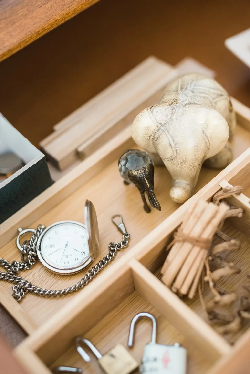 A drawer with dividers holding a pocket watch, keys and small everyday objects — the workshop on komono, the small items, through the KonMari® method