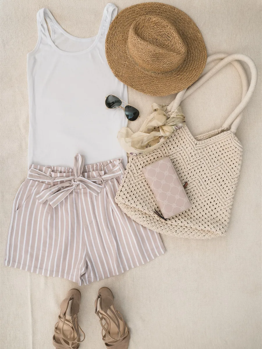 A straw hat, sunglasses, a silk scarf, a crochet bag and sandals laid out beside a top and shorts — shoes and clothes accessories in the KonMari® method