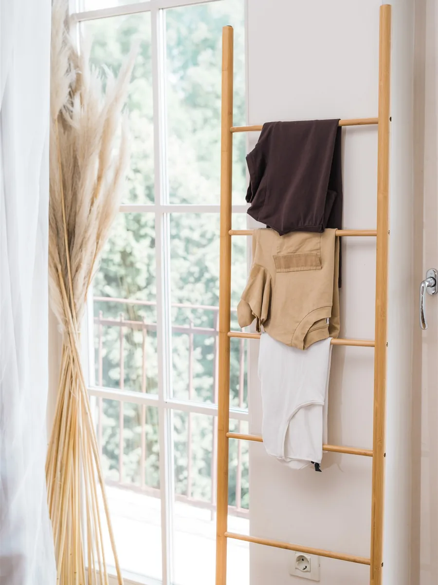 Clothes folded over a wooden ladder by a window — decluttering and organizing clothes the KonMari® way