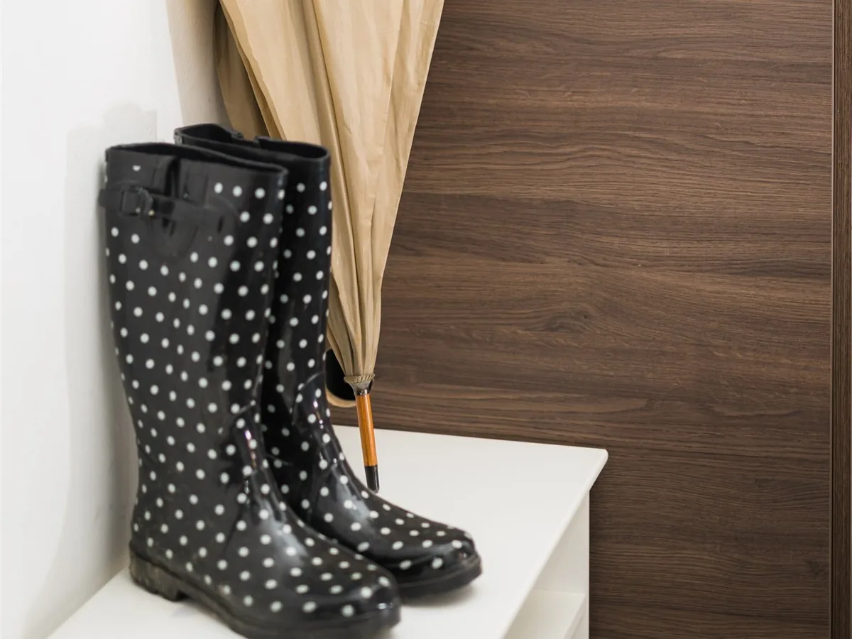 Black polka-dot rubber boots and a beige umbrella in a hallway