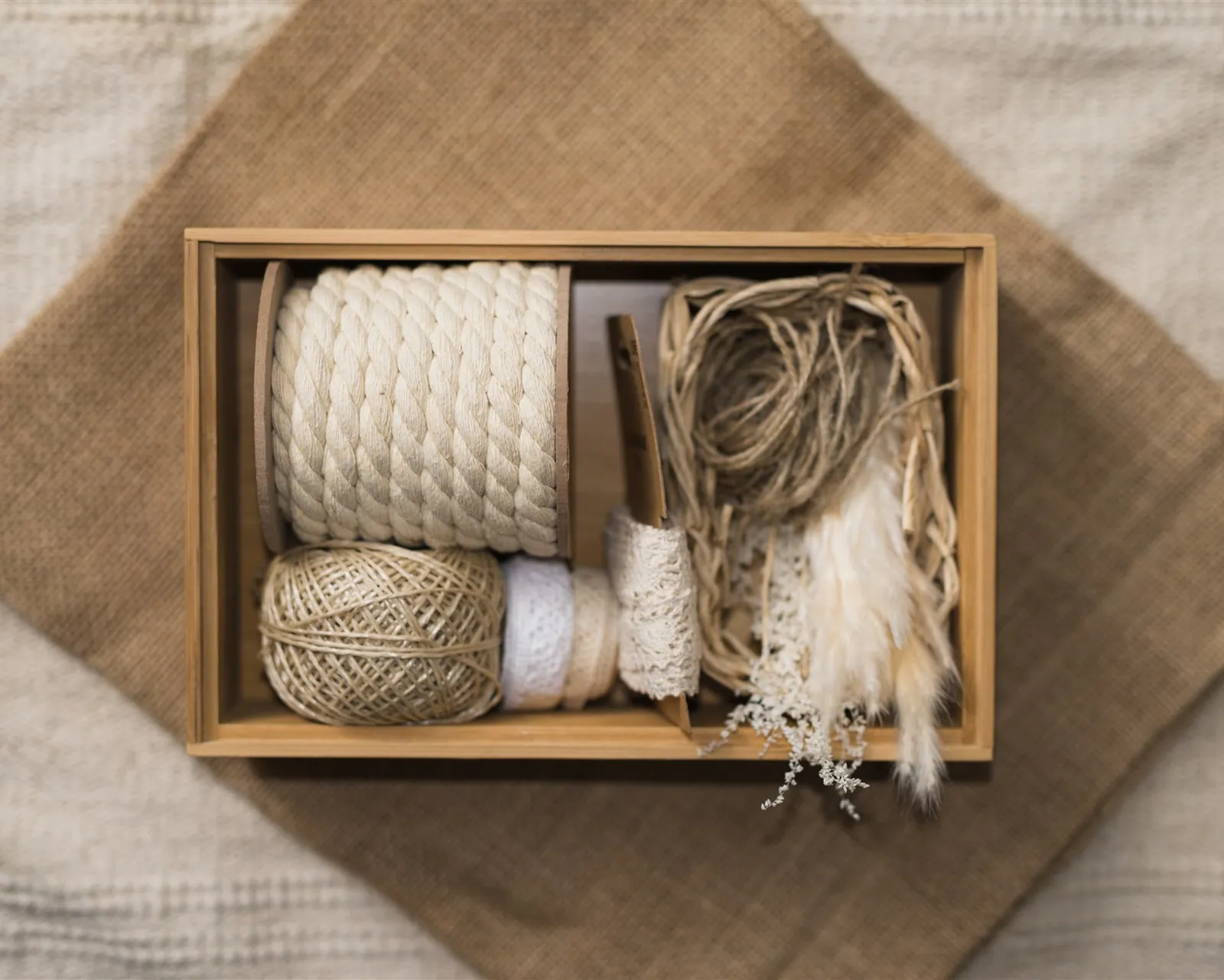 A wooden box with twine, ribbons and lace on a linen pouch — storing komono the KonMari® way