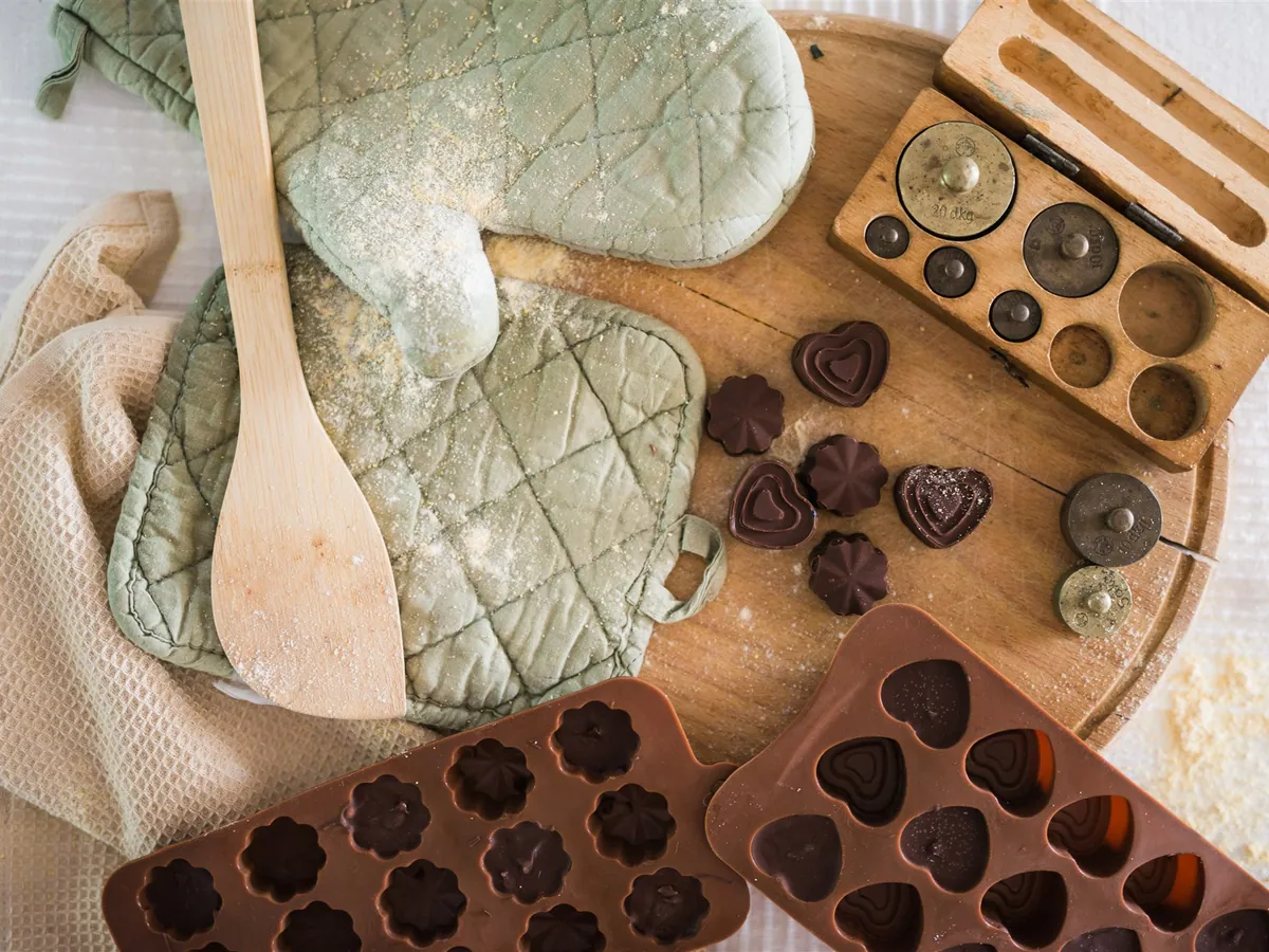 Green oven mitts, a wooden spoon, antique scales and chocolate moulds
