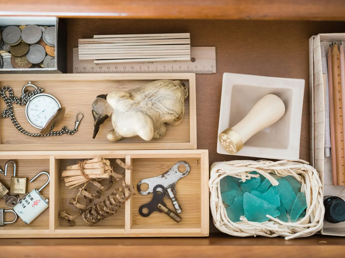 A drawer with wooden dividers: a pocket watch, padlocks, keys, coins and sea glass