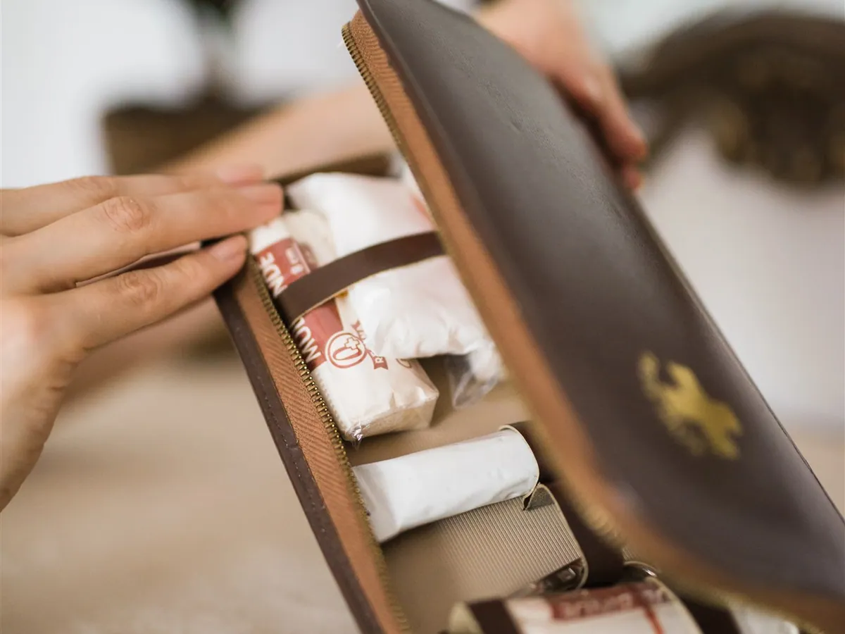 A leather travel case holding medicines, held open in both hands