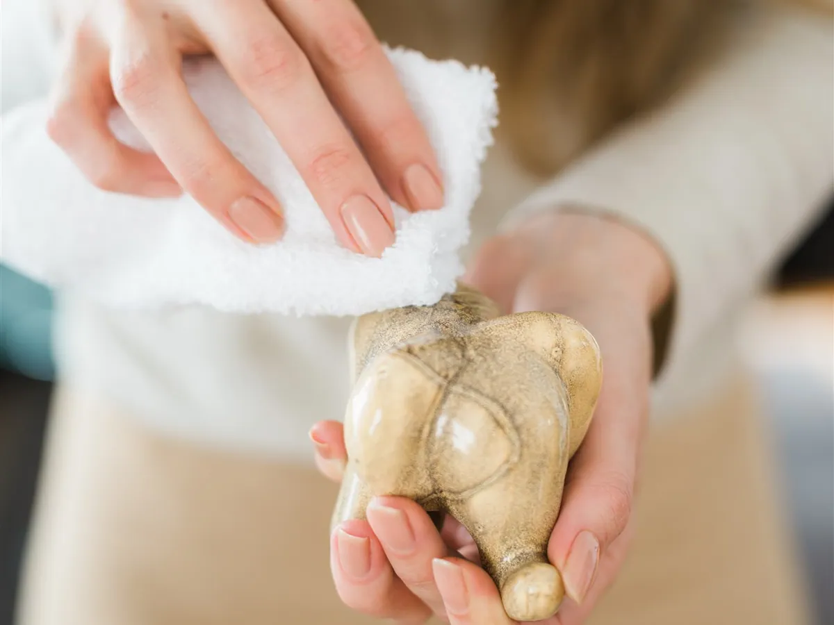 A woman wiping a small stone figurine with a soft cloth
