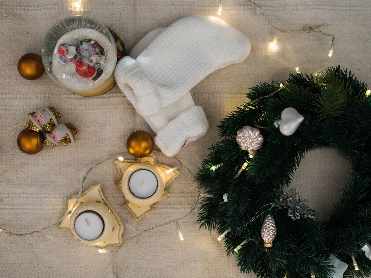 Christmas ornaments, a snow globe, knitted mittens and a lit wreath