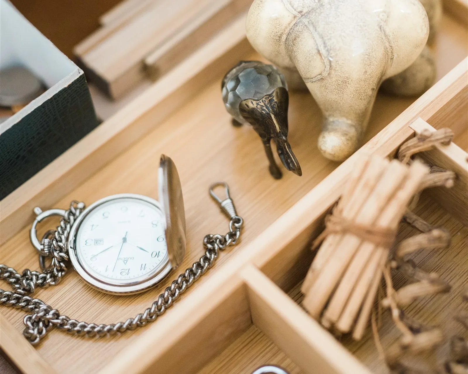 A drawer with wooden compartments, a pocket watch and small objects — komono, the fourth KonMari® category