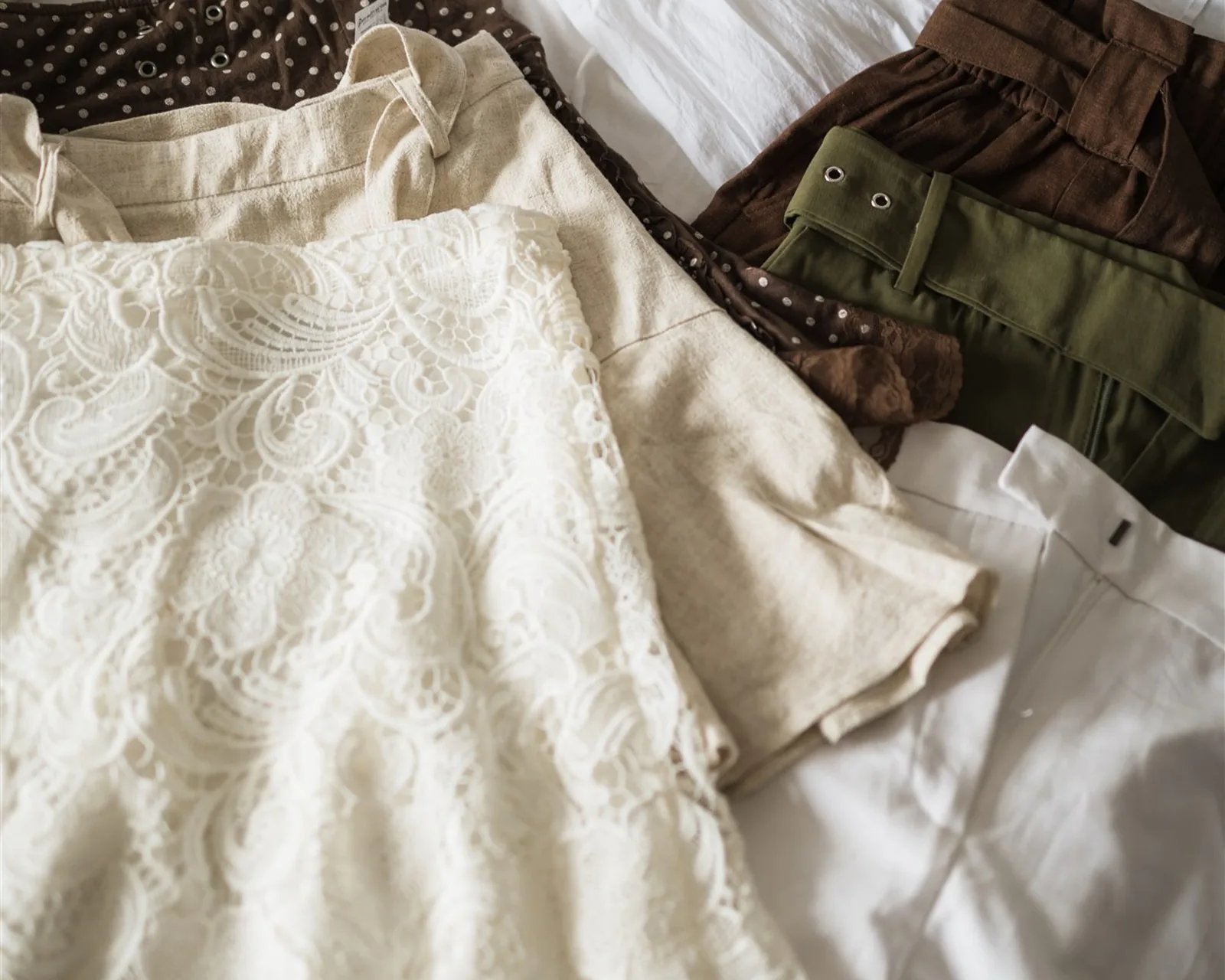 Folded skirts, trousers and blouses on a bed — every piece of clothing gathered into one pile
