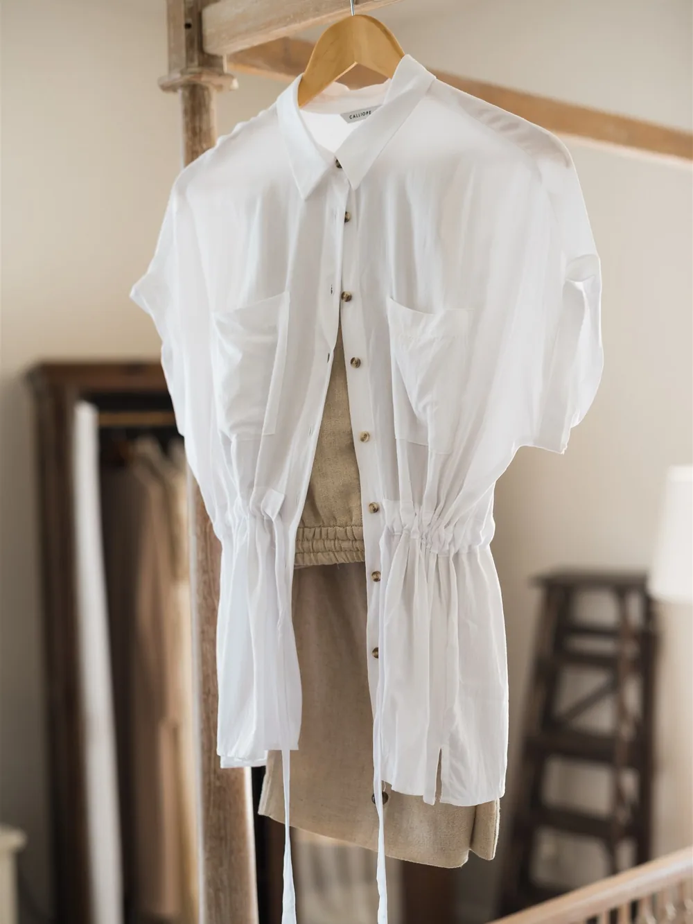 A white blouse on a wooden hanger beside a wardrobe — clothing that is better hung than folded