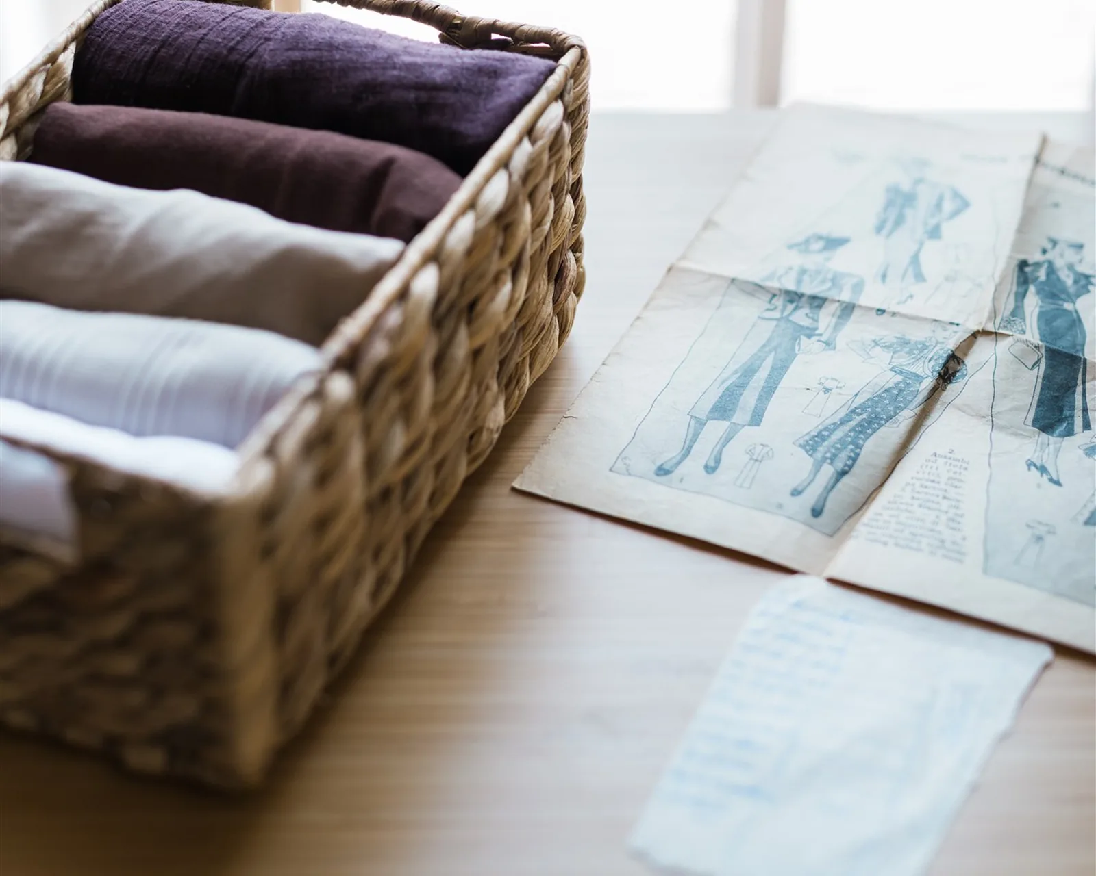 A woven basket with clothes folded upright on a wooden table — storing clothes the KonMari way