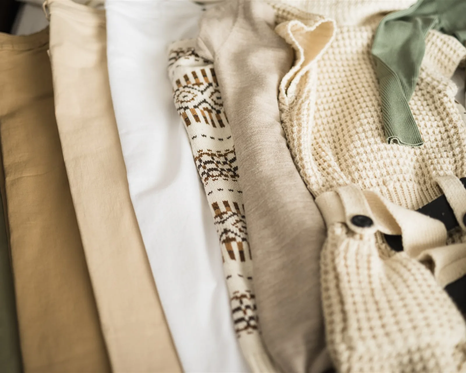 Ladica s okomito složenom odjećom u bež i zelenim tonovima — slaganje odjeće u ladici po KonMari® metodi