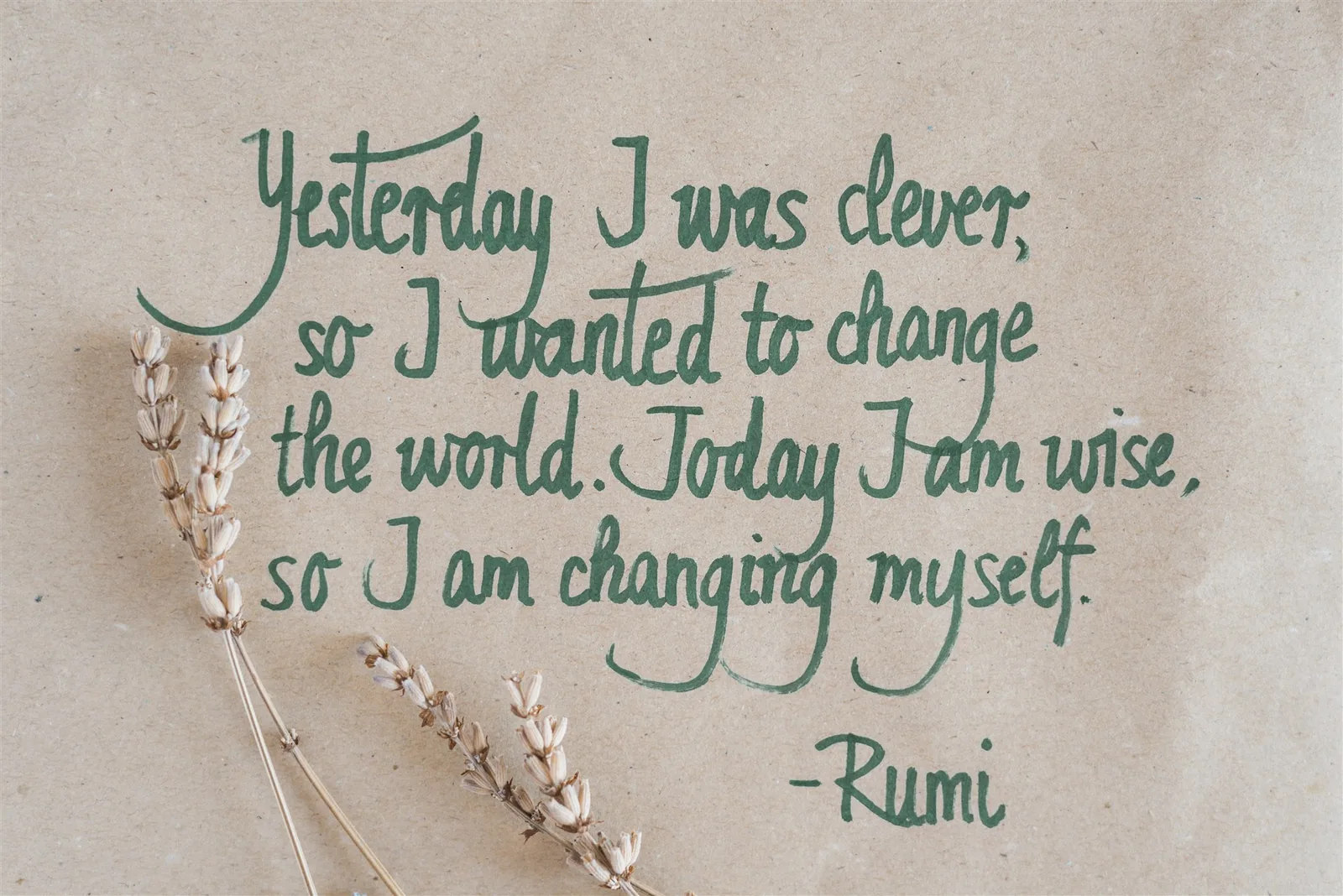 A handwritten Rumi quote in green ink on recycled paper, with dried lavender