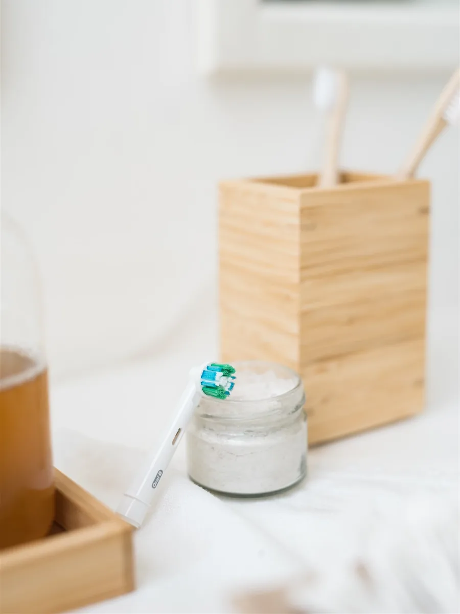 A jar of home-made toothpaste and bamboo toothbrushes in a wooden holder