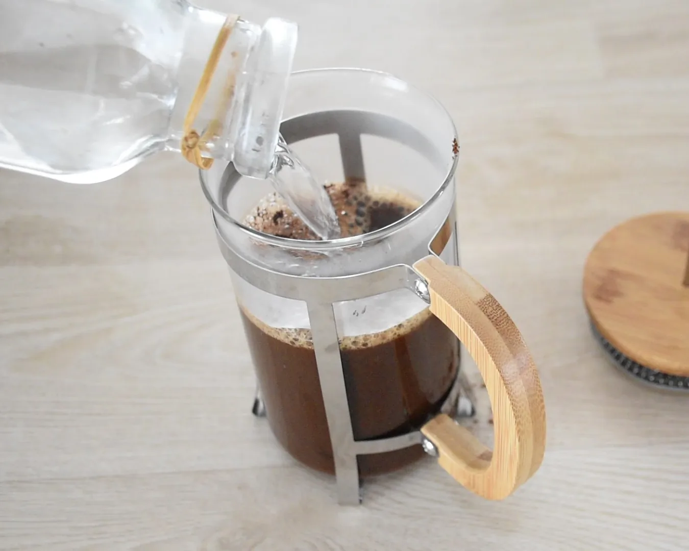 Hot distilled water being poured over ground coffee in a French press