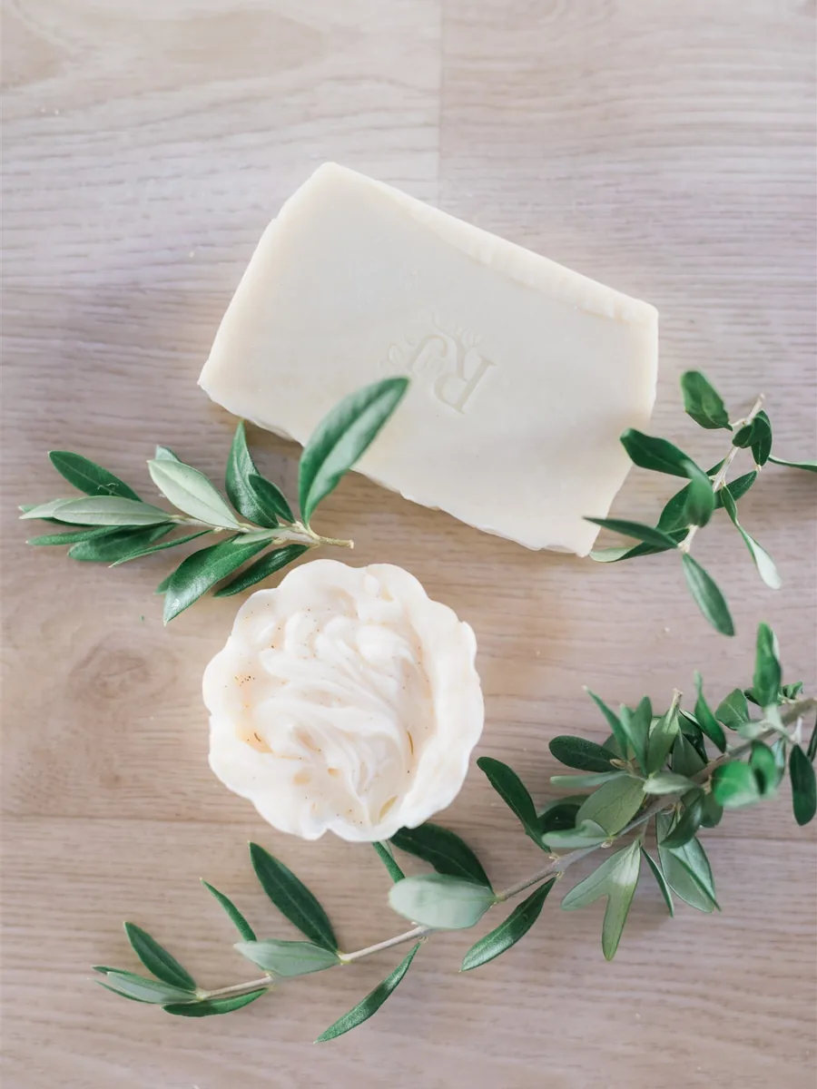 A castile soap bar stamped with the Root of Joy mark beside olive branches