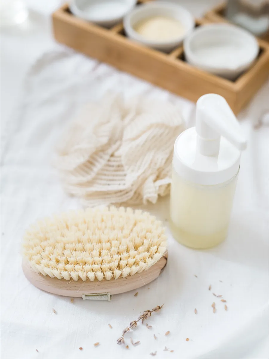 A pump bottle of homemade liquid soap beside a wooden brush and cotton cloths