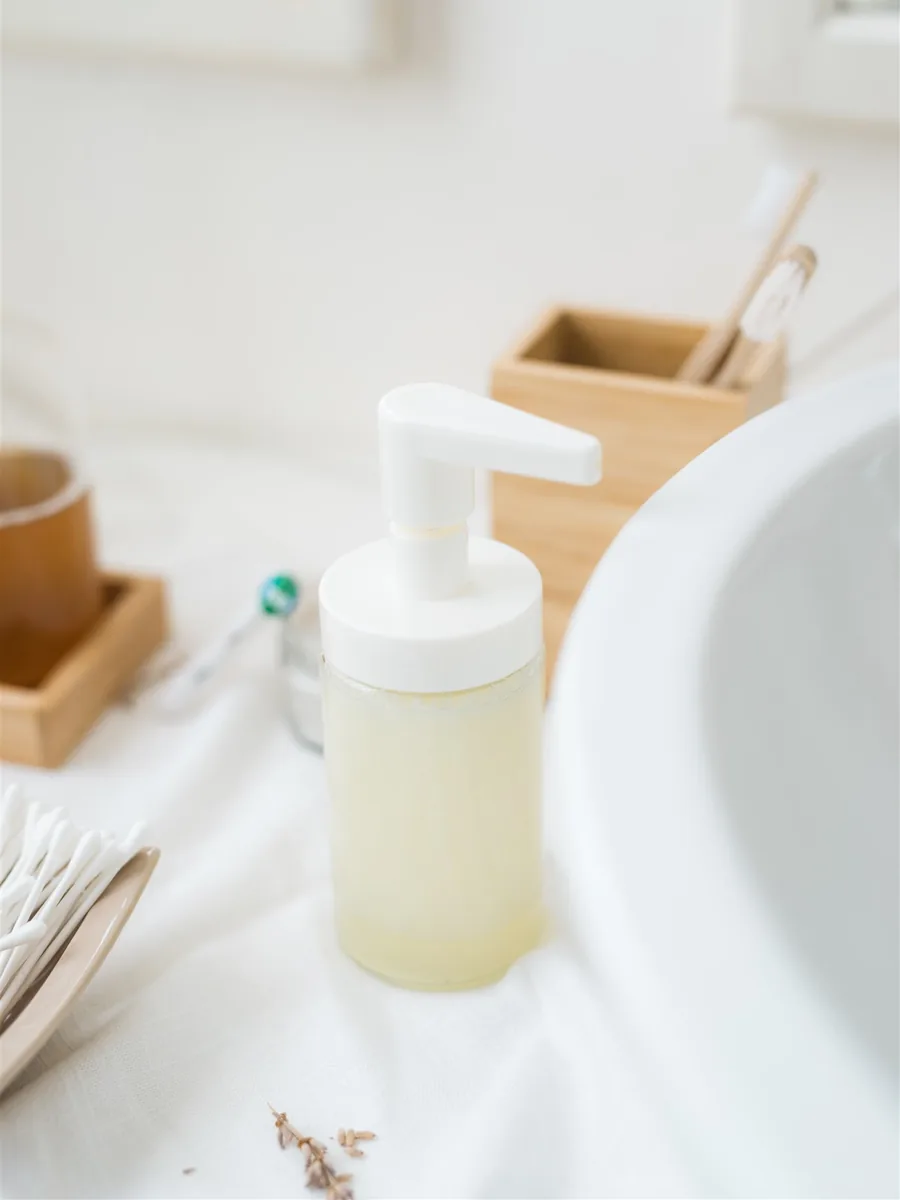 A pump bottle of homemade liquid soap beside a washbasin